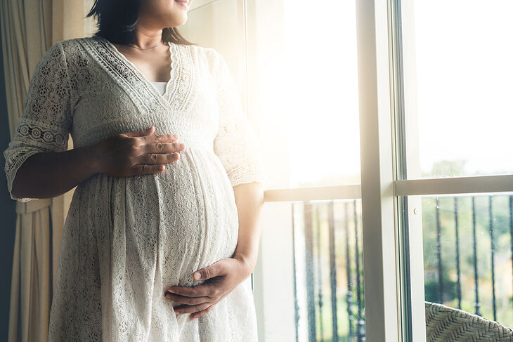 Zwangere vrouw houdt haar buik vast voor de mama monitor van 24baby