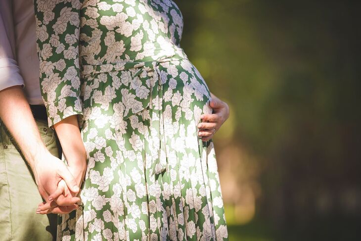 Zwangere vrouw houdt haar buik vast voor de mama monitor van 24baby